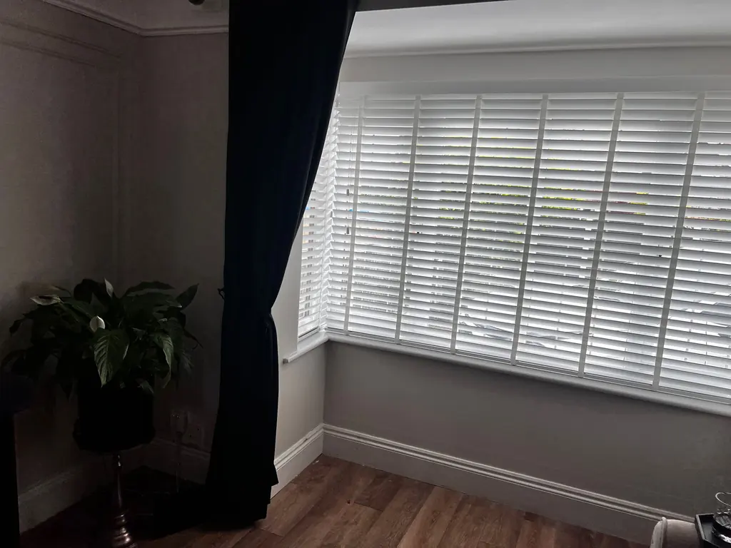 White slatted blind fitted within a bedroom window recess