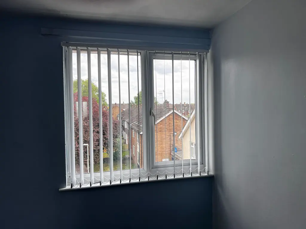 White vertical blind fitted to a window in a blue room