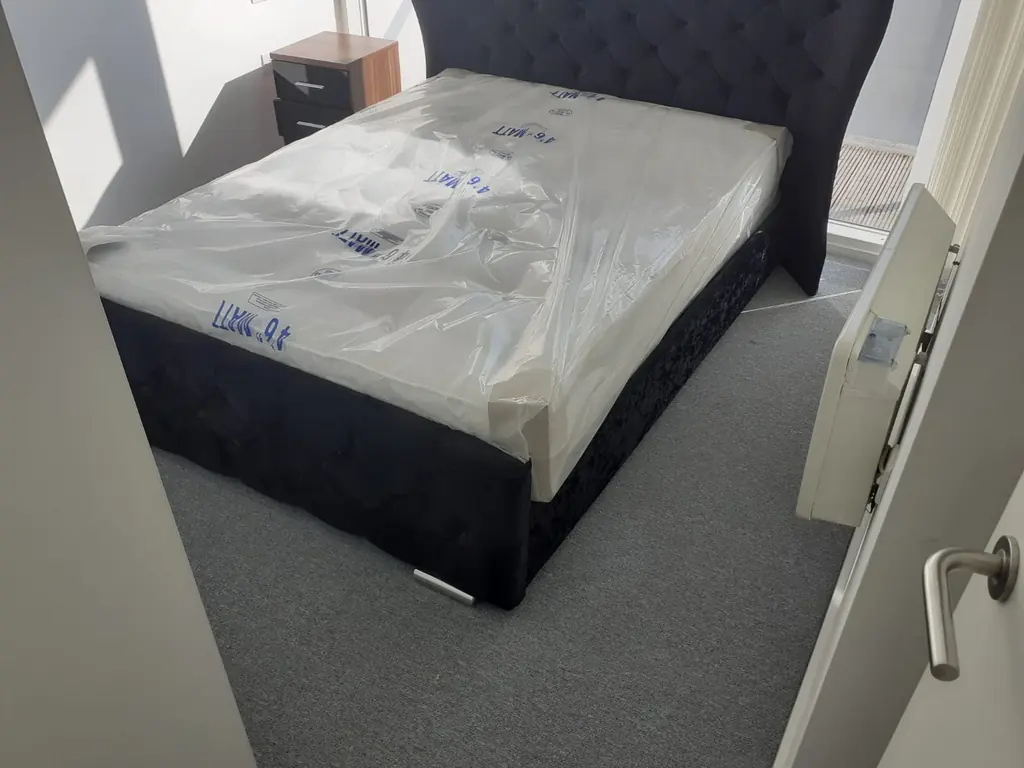 Grey fitted carpet around an upholstered bedroom bed