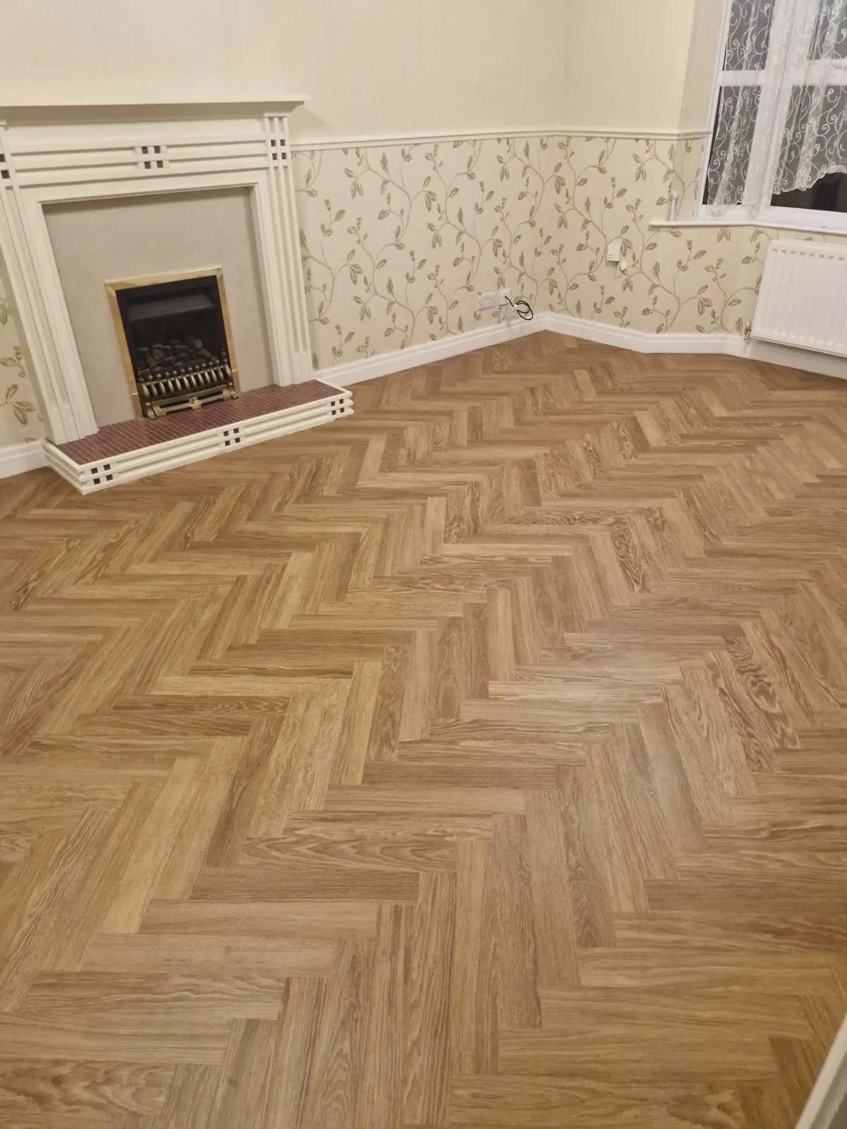 Completed wood-look herringbone floor beside a fireplace