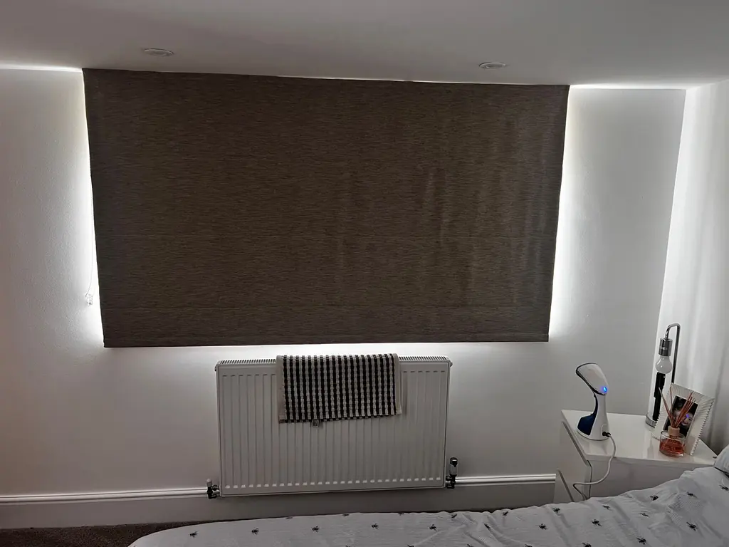 Neutral fabric roller blind lowered across a wide bedroom window