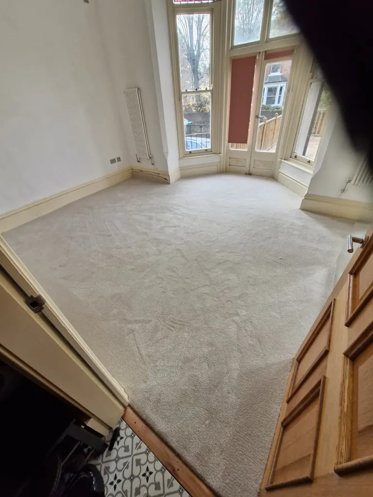 Pale fitted carpet extending across a bay-window room