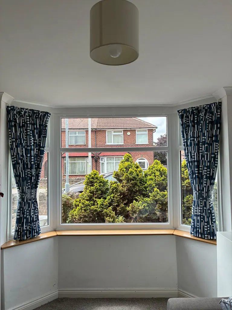 Blue patterned curtains fitted around an open bay window