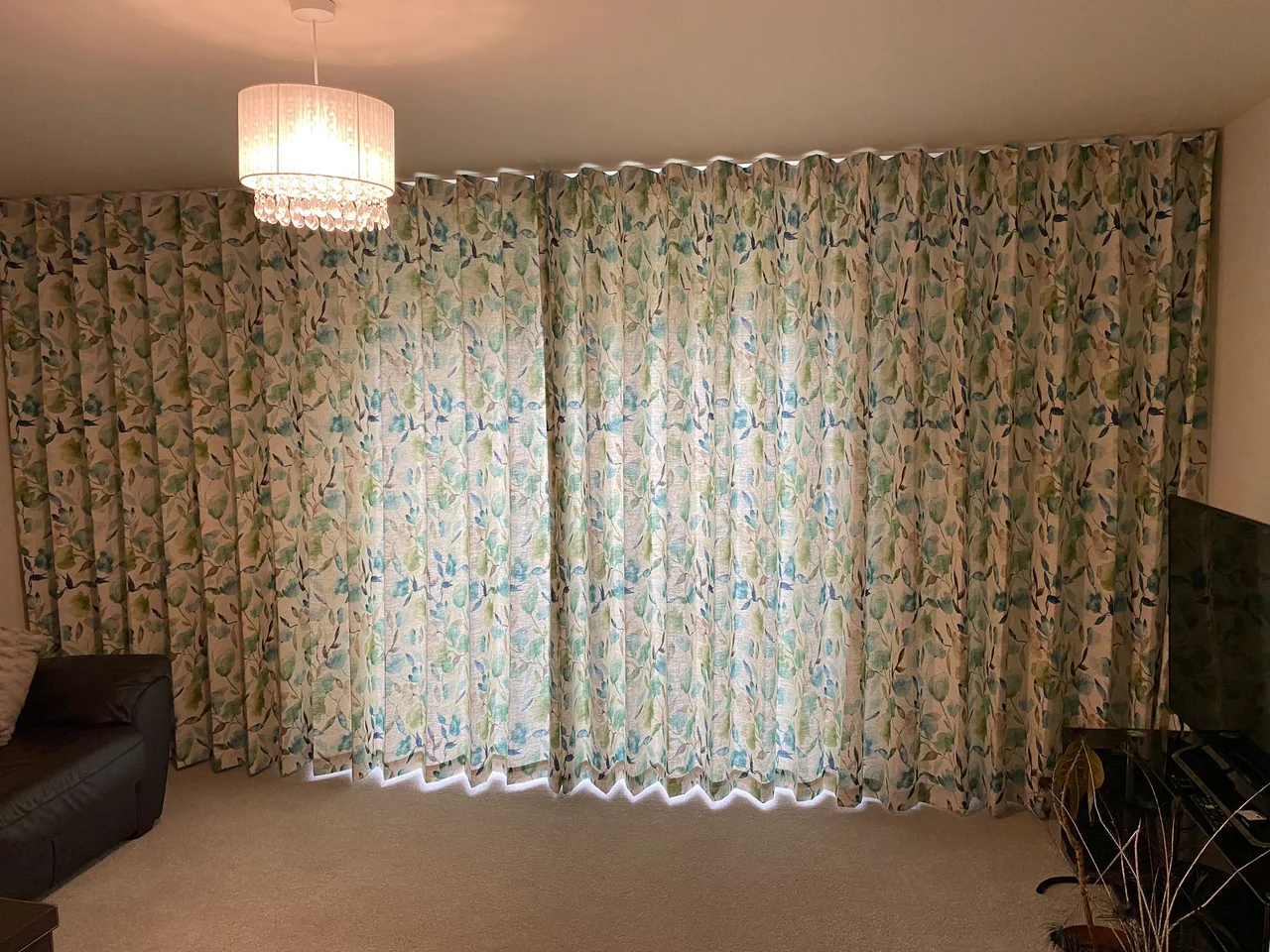 Full-length blue and green leaf-patterned curtains closed across a wide opening