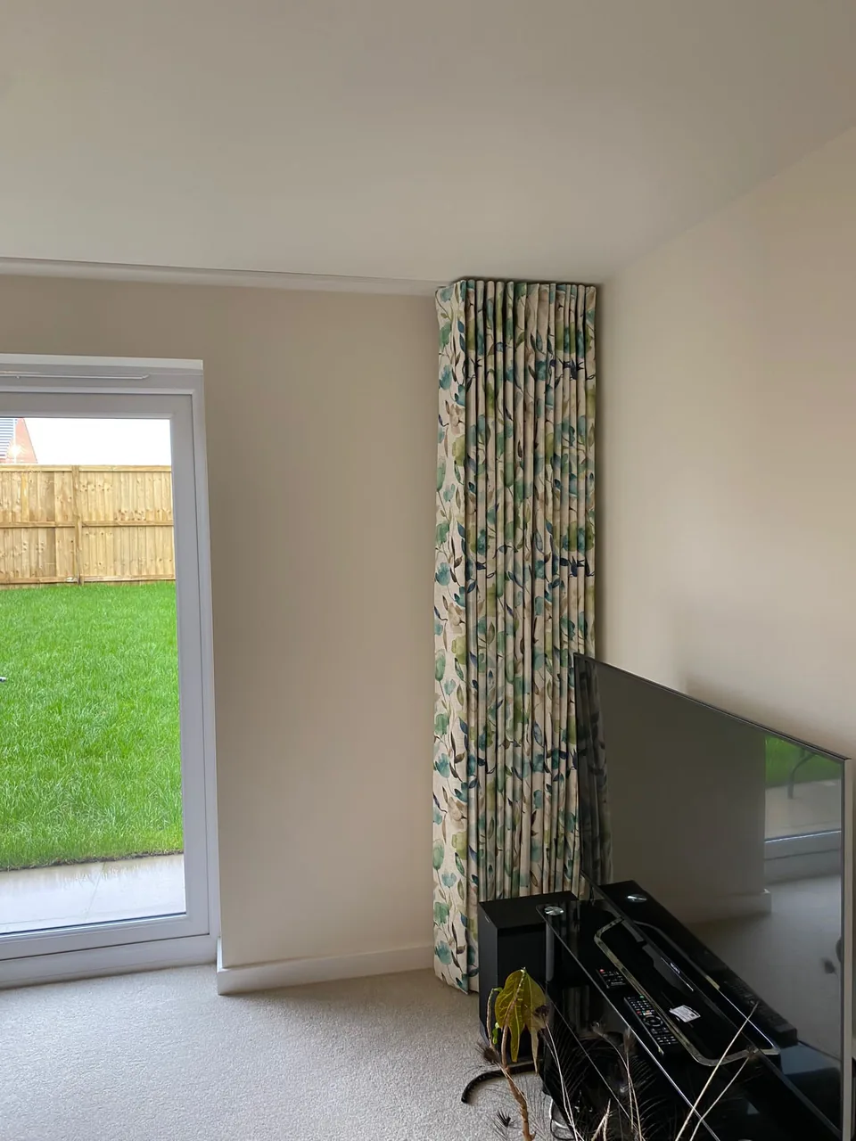 Leaf-patterned full-length curtain drawn back beside a glazed door