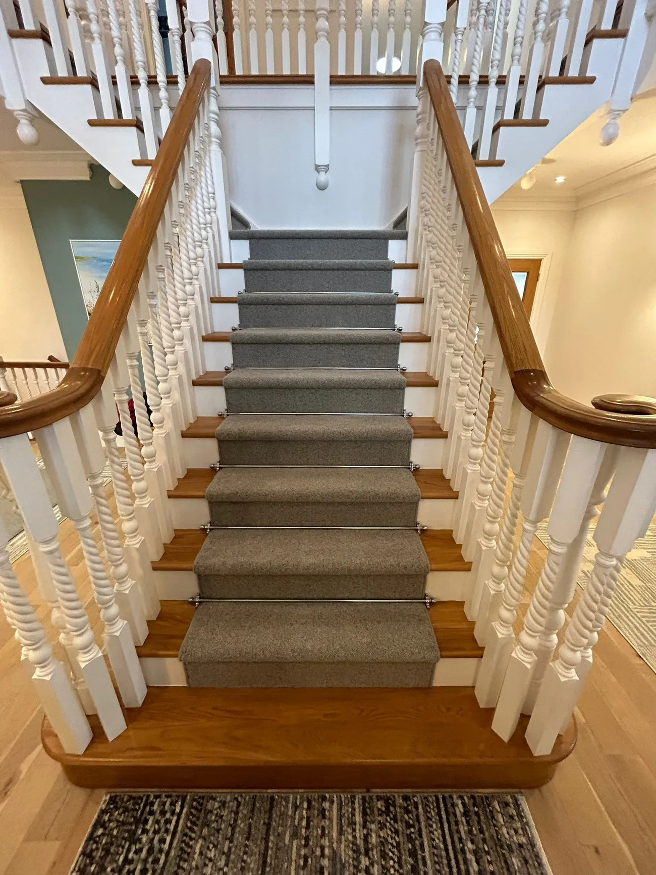 Grey carpet runner with stair rods on a timber staircase, viewed from the front