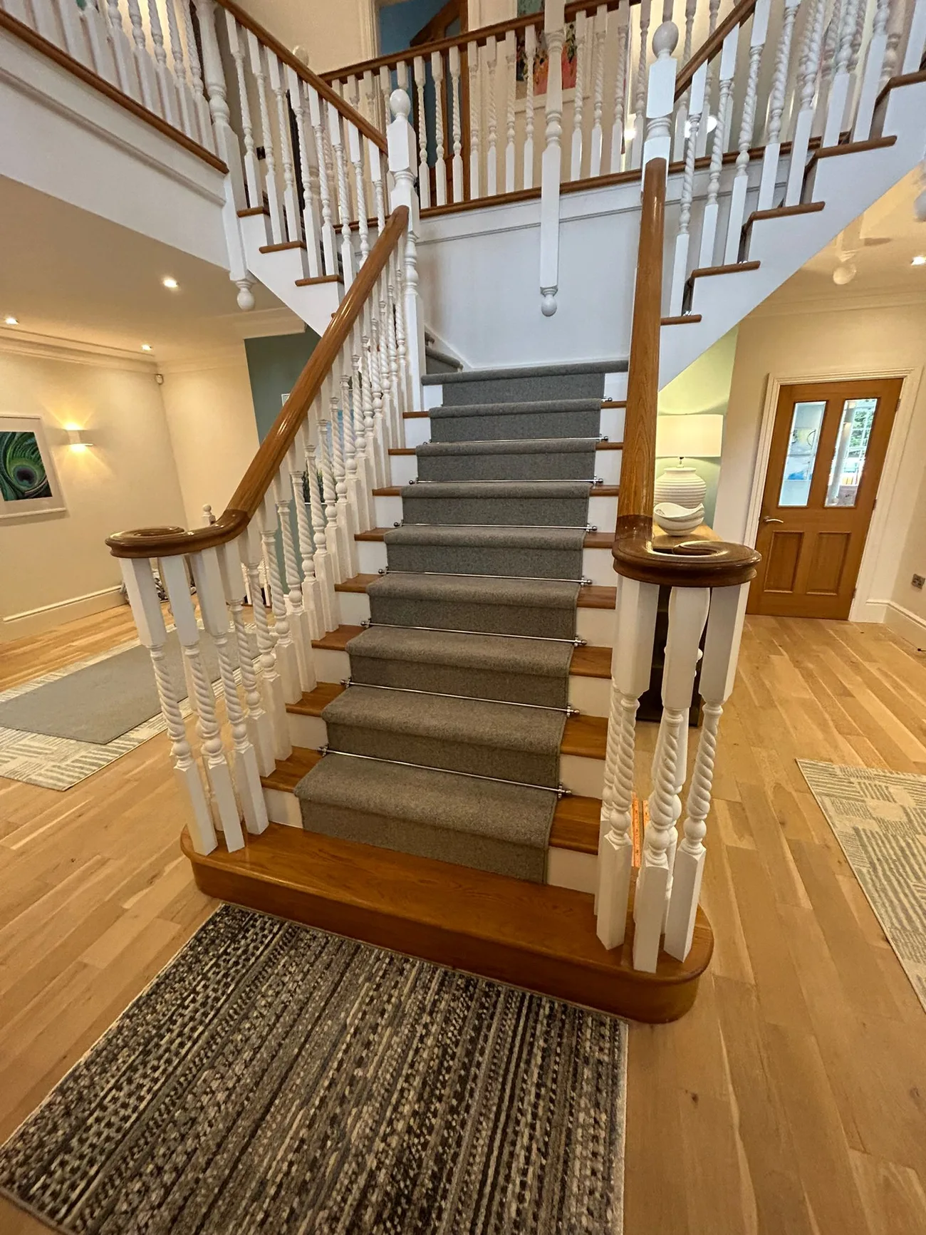 A wider view of the fitted grey runner and timber staircase in the hall