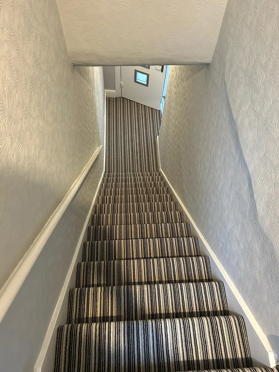 Contrasting striped carpet fitted to a staircase and hallway below