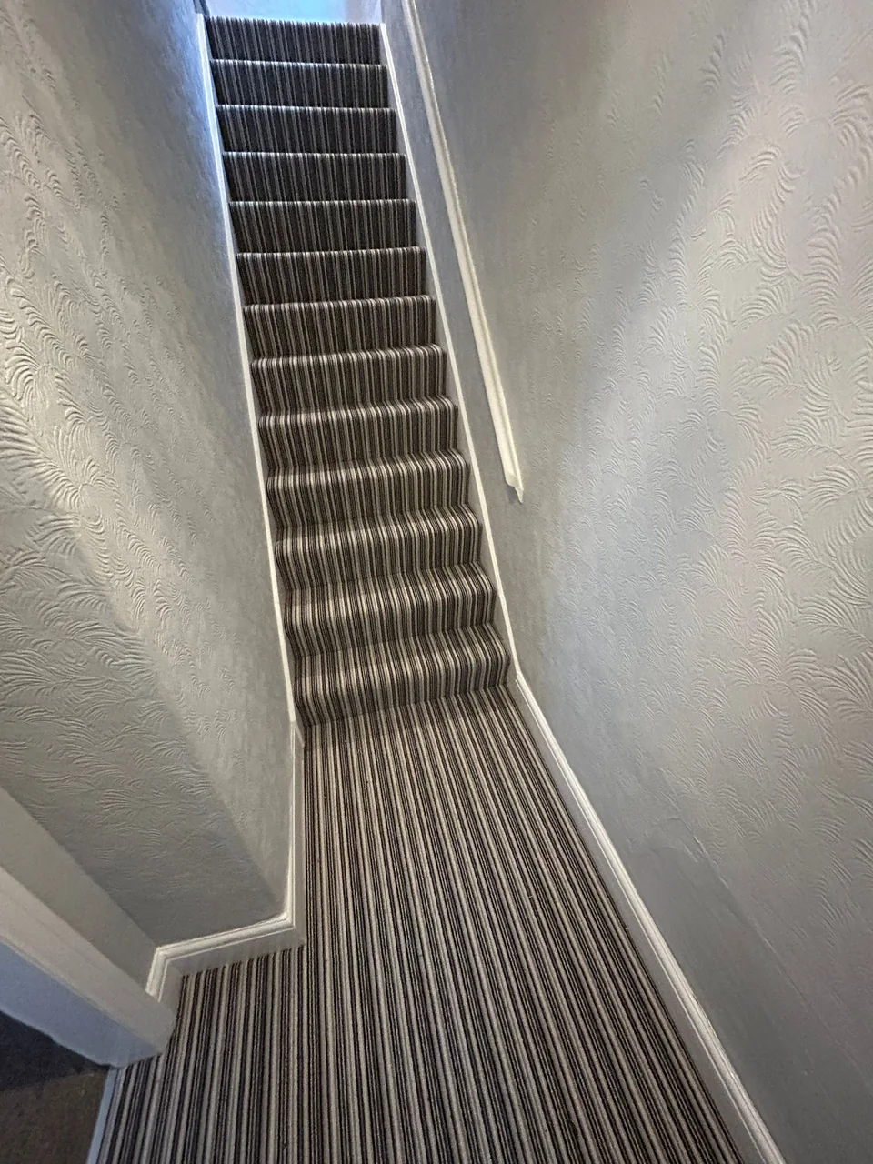 Striped carpet continuing from the staircase around the landing