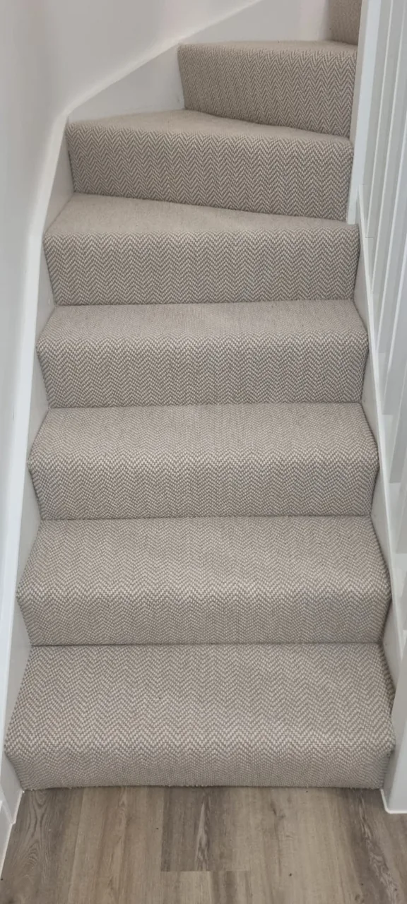 Light textured carpet fitted across the treads and risers of a turning staircase